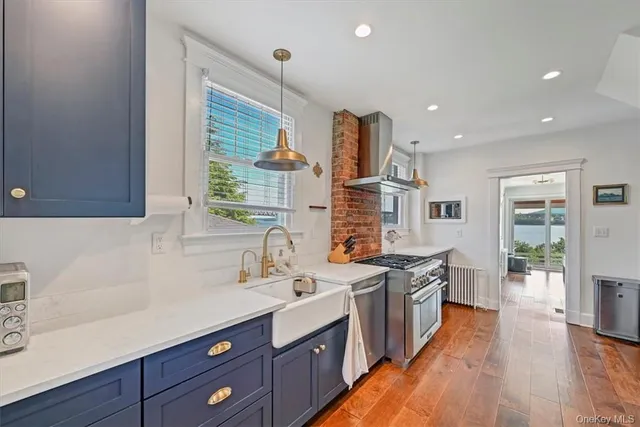 a kitchen with stainless steel appliances a sink stove and wooden floor