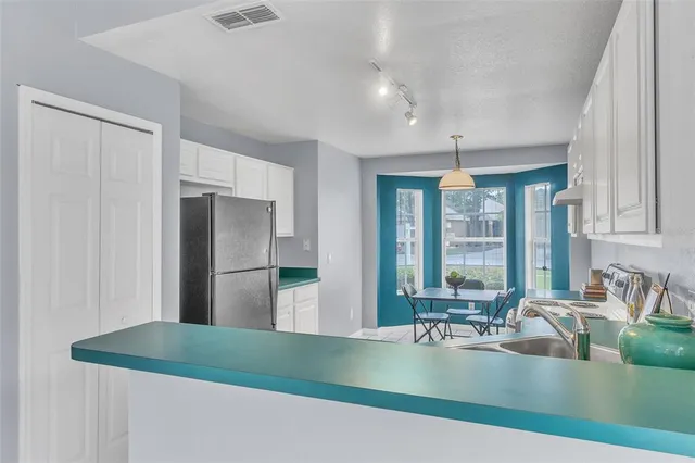 a kitchen with stainless steel appliances granite countertop a refrigerator a sink a stove and white cabinets with wooden floor