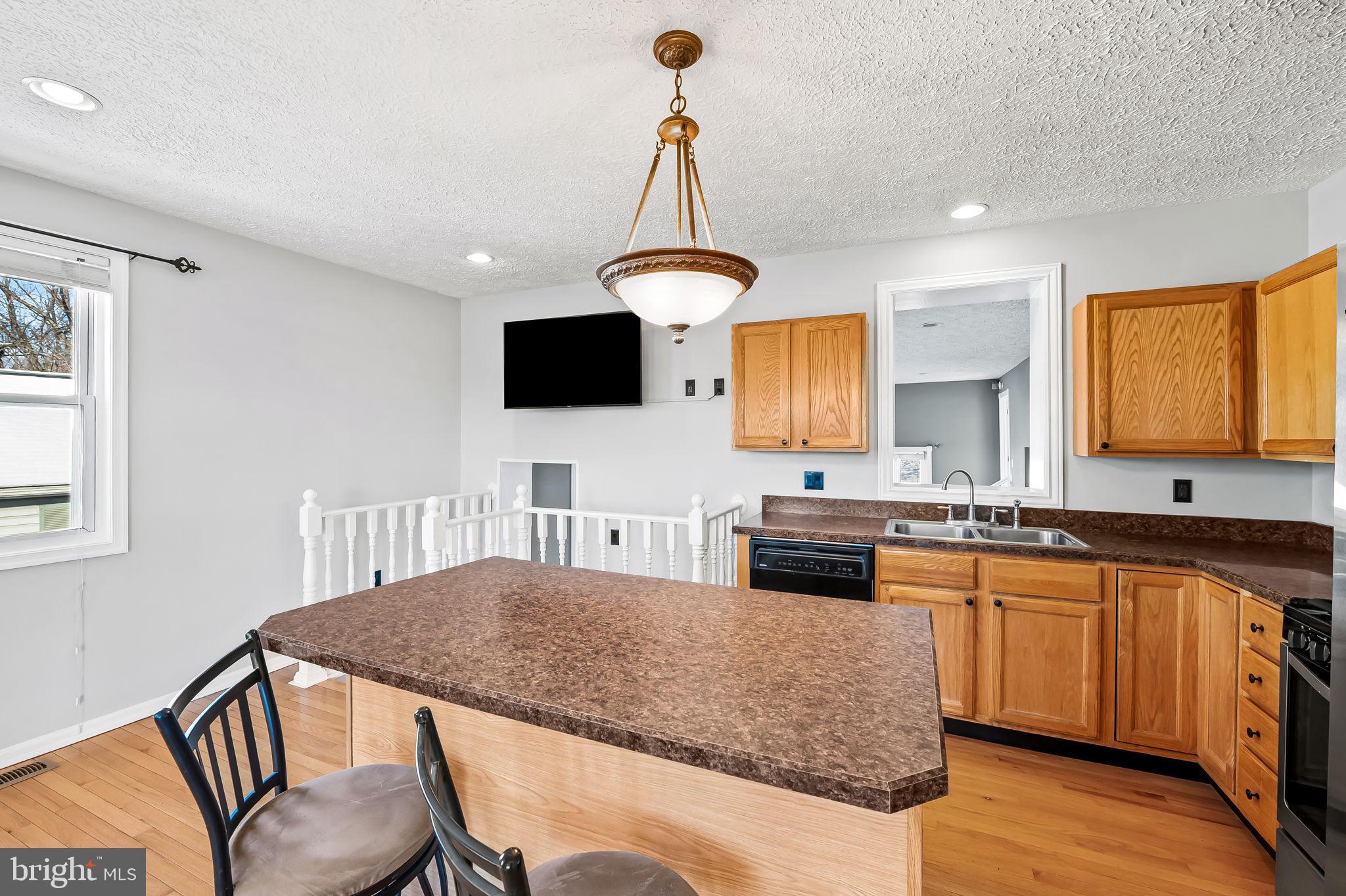 4222 Klosterman Avenue Nottingham, MD 21236 - Photo 13 of 43 a kitchen with kitchen island granite countertop a sink and a stove top oven with wooden floor