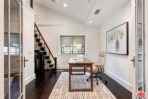 a workspace with wooden floor and paintings on the walls