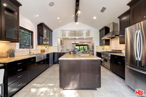 a large kitchen with stainless steel appliances kitchen island granite countertop a stove a sink dishwasher and a refrigerator
