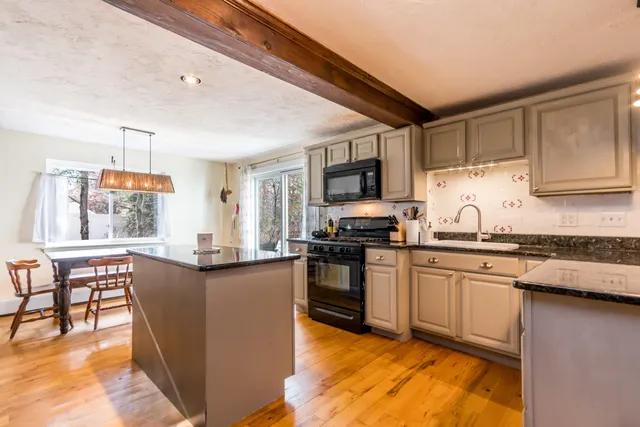 a kitchen with stainless steel appliances granite countertop a stove top oven a sink a dining table and chairs