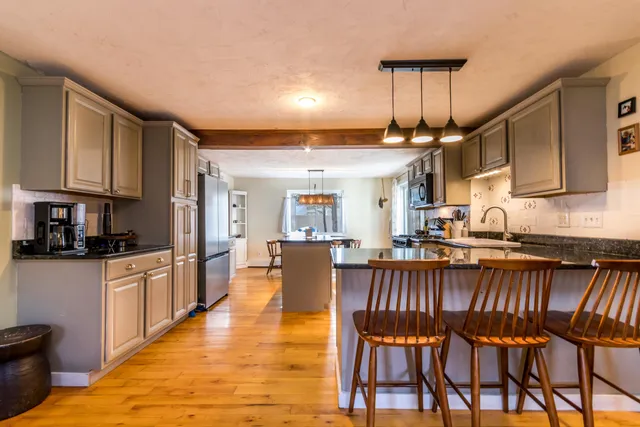 a kitchen with granite countertop a table chairs microwave and cabinets