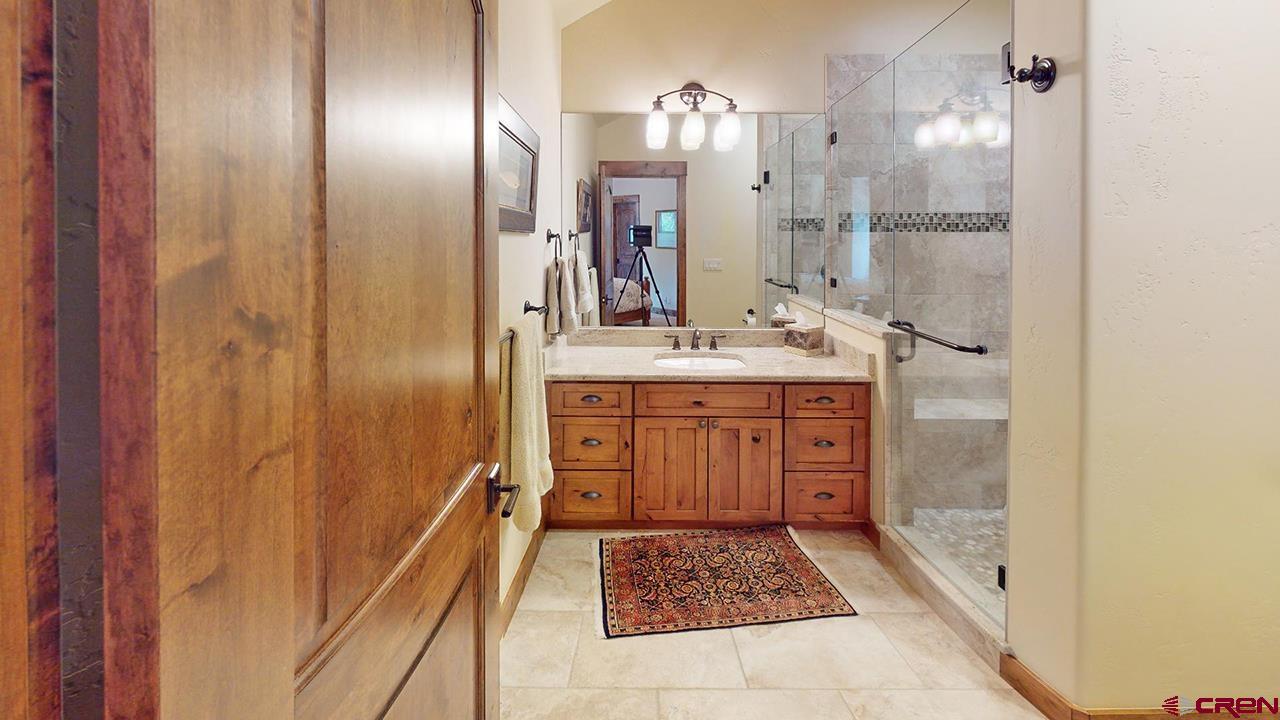610 Red Rock Road Durango, CO 81301 - Photo 31 of 35 a bathroom with a granite countertop sink a mirror and a shower