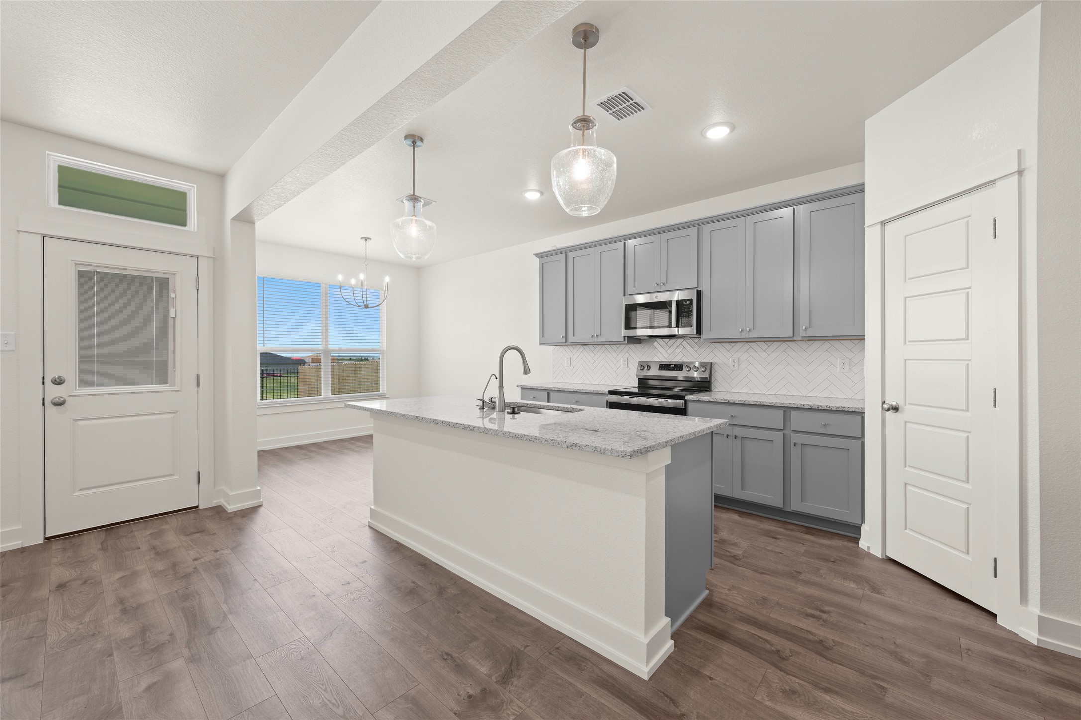 564 Gus Loop Georgetown, TX 78626 - Photo 8 of 32 a kitchen with kitchen island granite countertop a sink cabinets and wooden floor