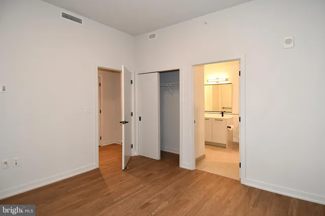 a view of an empty room with wooden floor and a bathroom