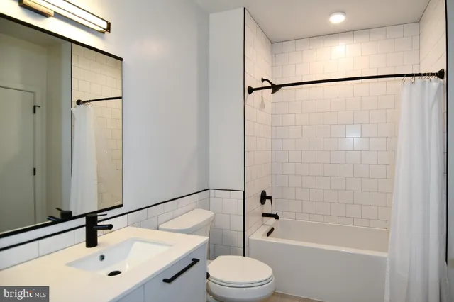a bathroom with a bathtub shower sink vanity and toilet