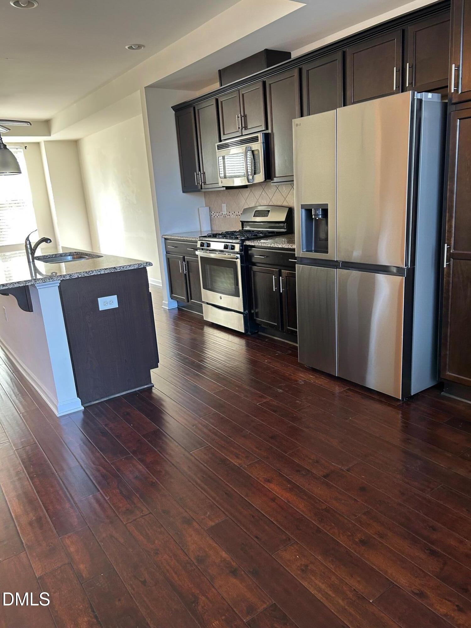 4110 Sykes Street Cary, NC 27519 - Photo 9 of 29 a kitchen with stainless steel appliances wooden floor and chairs