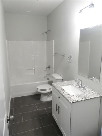 8071 County Road, Unit 436 Princeton, TX 75407 - Photo 5 of 8 a bathroom with a granite countertop sink a toilet and bathtub