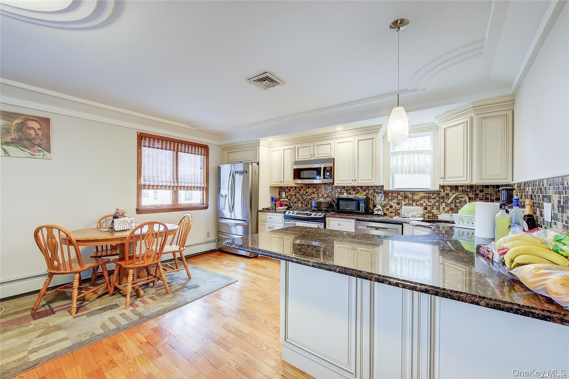 43-33 163rd Street Queens, NY 11358 - Photo 13 of 31 a kitchen with stainless steel appliances granite countertop a stove top oven a sink a dining table and chairs with wooden floor