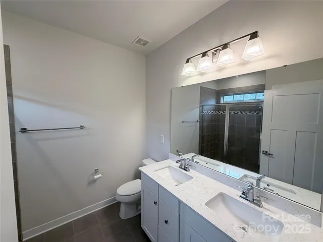 a bathroom with a double vanity sink toilet and mirror