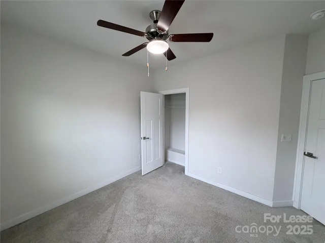 an empty room with a ceiling fan and carpet