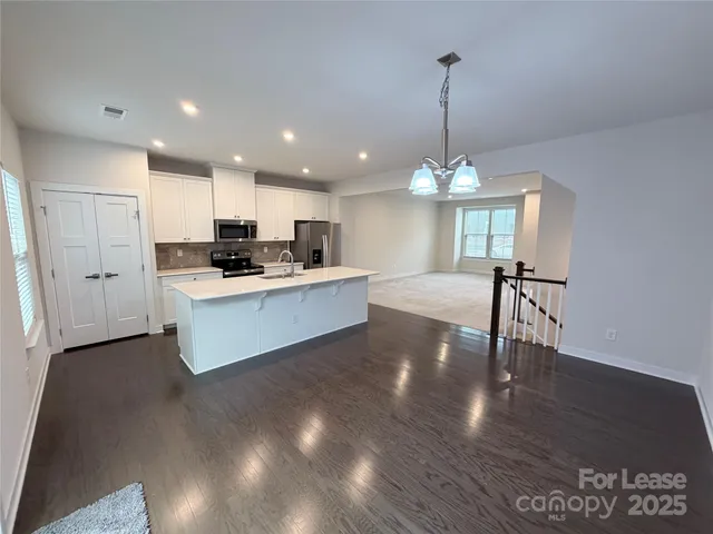 a kitchen with stainless steel appliances kitchen island granite countertop a stove a sink dishwasher and a dining table with wooden floor