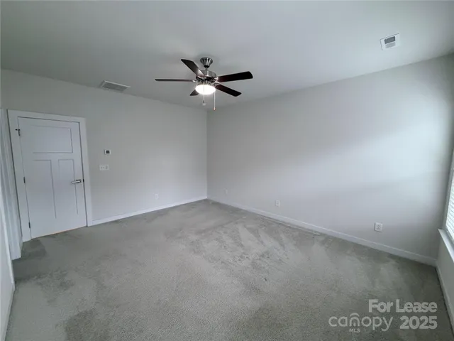 an empty room with a fan & a window
