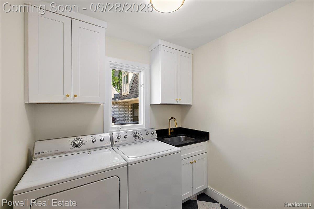 1447 Ravineview Court, Unit C12 Bloomfield Hills, MI 48304 - Photo 13 of 49 Laundry area featuring white shaker-style cabinetry, a built-in utility sink with a gold-tone faucet, and a black countertop