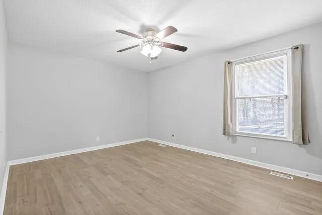 an empty room with windows and fan