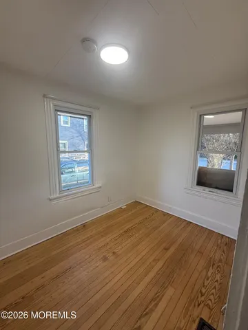 a view of an empty room with window and wooden floor