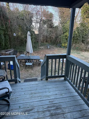 a view of a backyard with table and chairs potted plants and large tree