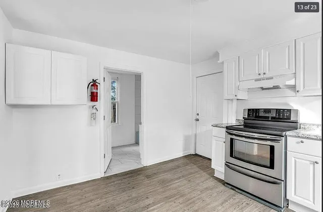 a kitchen with granite countertop white cabinets and stainless steel appliances