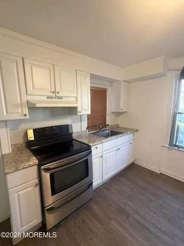 a kitchen with granite countertop white cabinets and appliances