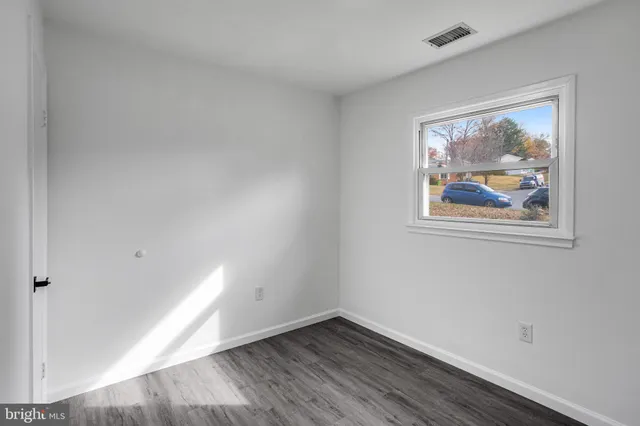 an empty room with wooden floor and window