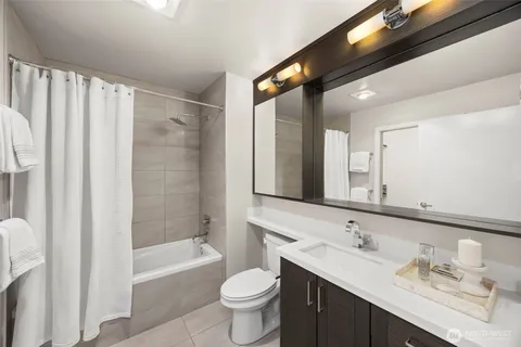 a bathroom with a double vanity sink toilet mirror and bathtub