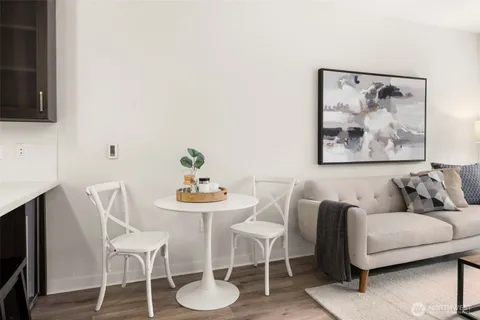 a living room with furniture a couch and a dining table with wooden floor