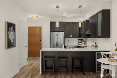 a kitchen with stainless steel appliances kitchen island granite countertop a table chairs microwave and sink