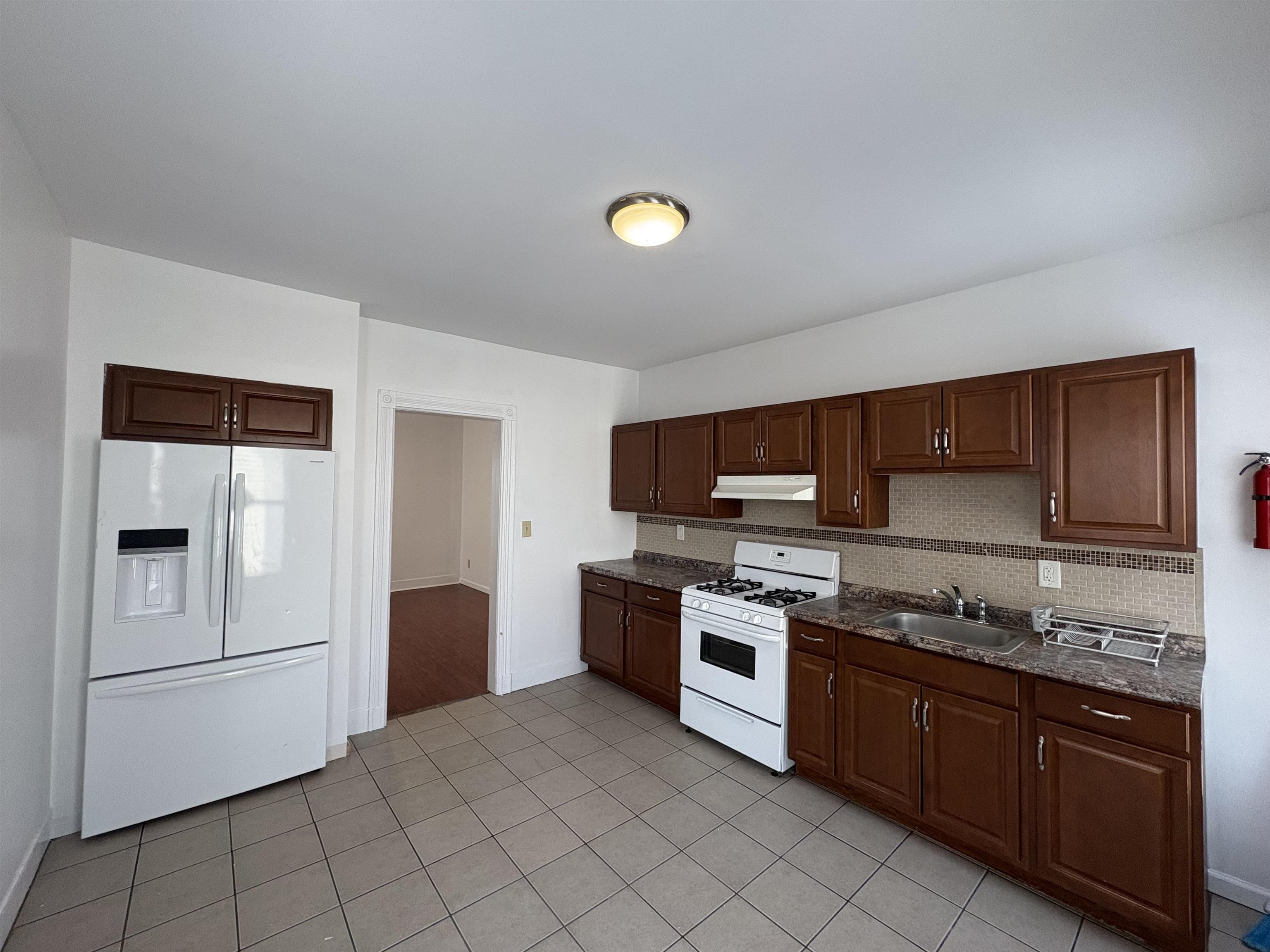 814 28th Street, Unit 2 Union City, NJ 07087 - Photo 5 of 12 a kitchen with a stove a sink and a refrigerator