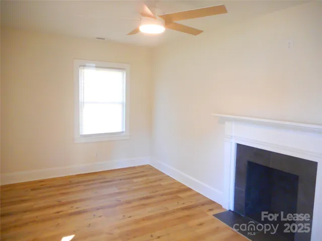 an empty room with wooden floor fireplace and windows