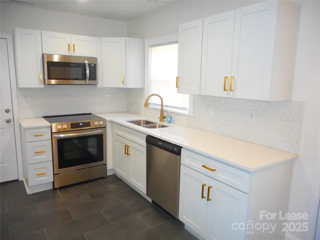 a kitchen with cabinets appliances a sink and a window