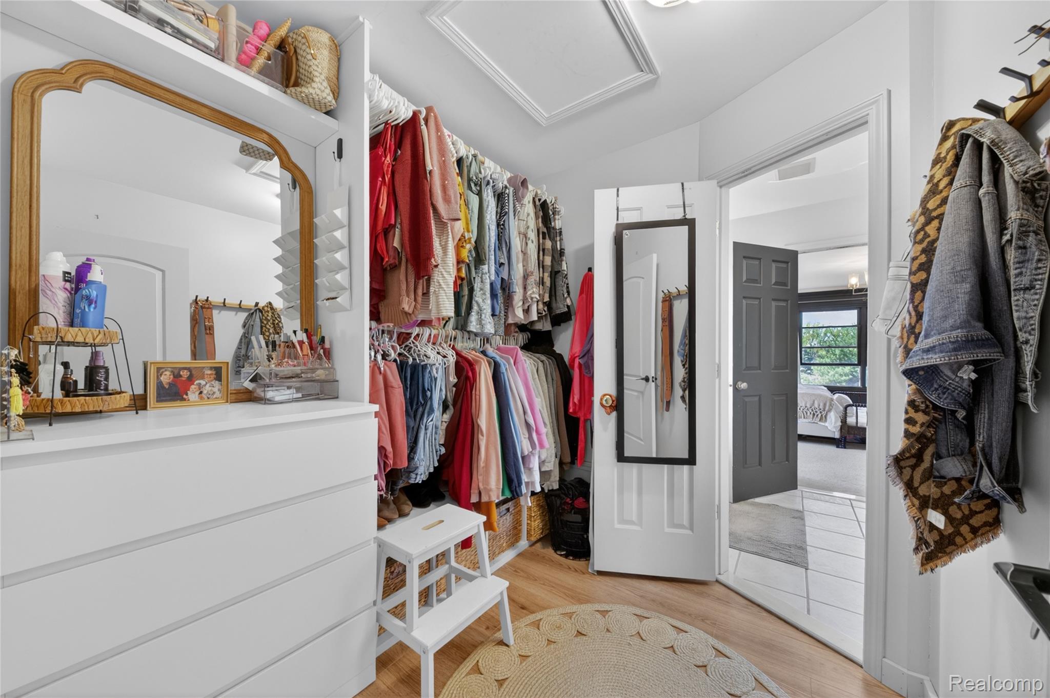 9191 Judd Road Fowlerville, MI 48836 - Photo 36 of 74 Spacious walk-in closet featuring wood-finish flooring, built-in shelving, and a white dresser with a large mirror