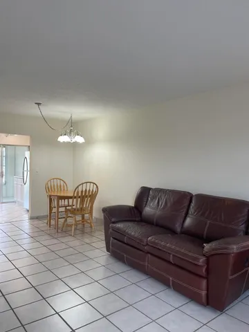 a living room with furniture a dining table and a chandelier