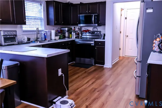 a kitchen with stainless steel appliances granite countertop a refrigerator a sink dishwasher a stove and black cabinets with wooden floor