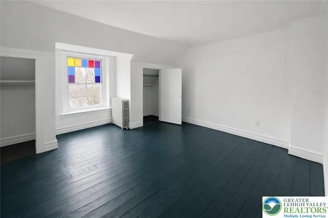 a view of an empty room with wooden floor and closet