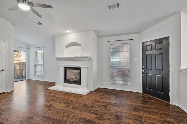an empty room with wooden floor fireplace and windows
