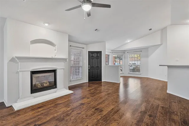 a view of an empty room with wooden floor fireplace and a window