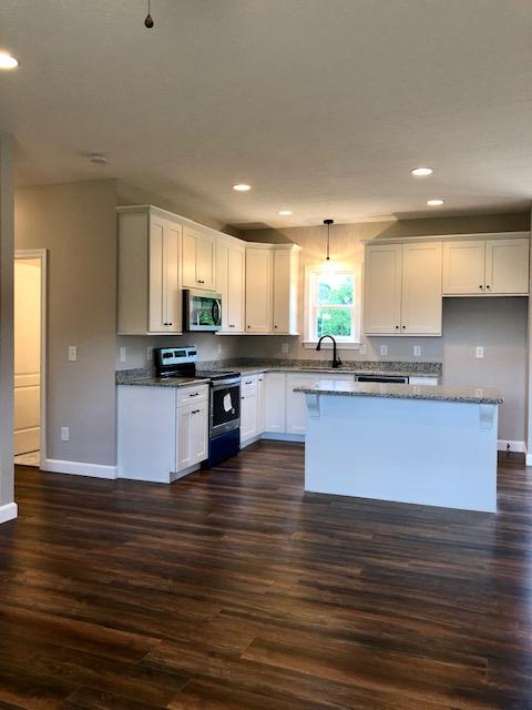 353 Lear Road Portland, TN 37148 - Photo 5 of 14 a large kitchen with granite countertop a stove top oven a sink dishwasher and white cabinets with wooden floor