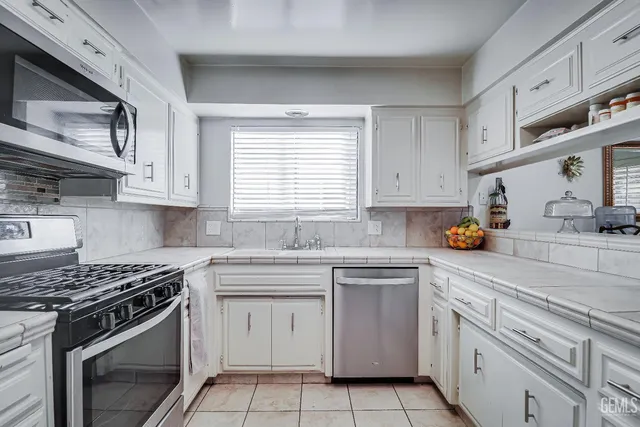 a kitchen with white cabinets stainless steel appliances and sink