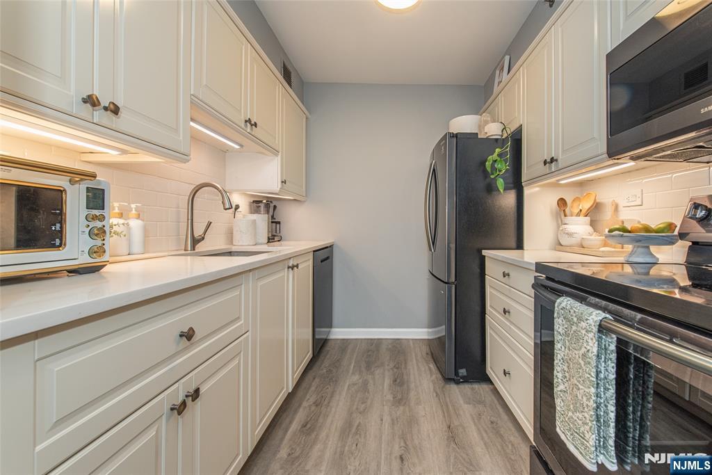 300 Main Street, Unit 211 Little Falls, NJ 07424 - Photo 13 of 30 a kitchen with cabinets and stainless steel appliances