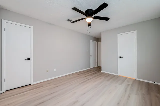 an empty room with wooden floor and ceiling fan