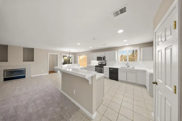 a large white kitchen with a stove a sink dishwasher and a microwave oven on the kitchen countertops