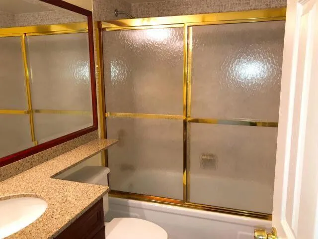 a bathroom with a granite countertop shower and a sink
