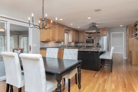 a kitchen with stainless steel appliances kitchen island granite countertop a table chairs and a refrigerator