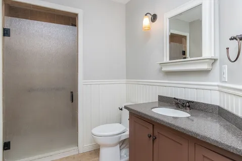 a bathroom with a granite countertop sink toilet and mirror