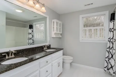 a bathroom with a granite countertop sink mirror vanity and a toilet