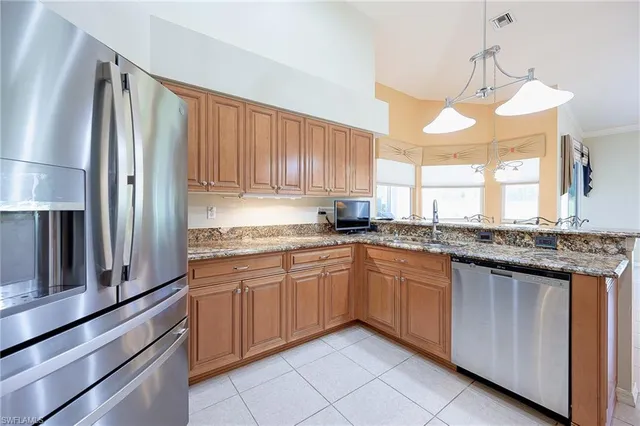 a kitchen with granite countertop stainless steel appliances a sink and a refrigerator