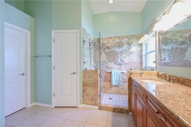 a bathroom with a granite countertop sink a mirror and shower