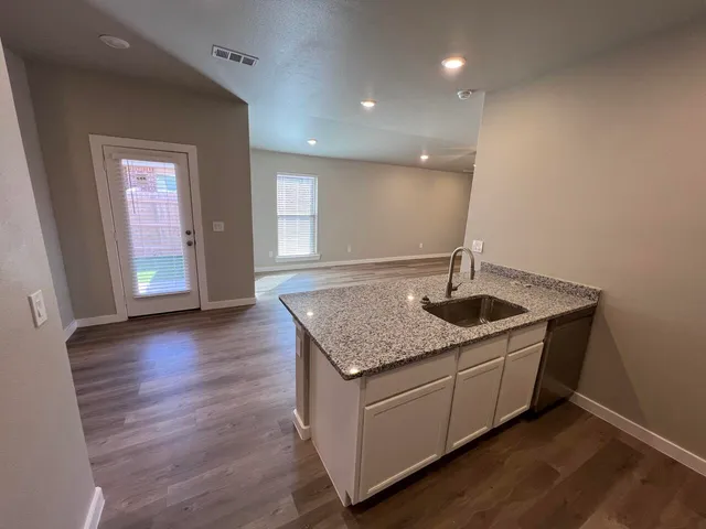 a kitchen with stainless steel appliances granite countertop a sink and a wooden floor