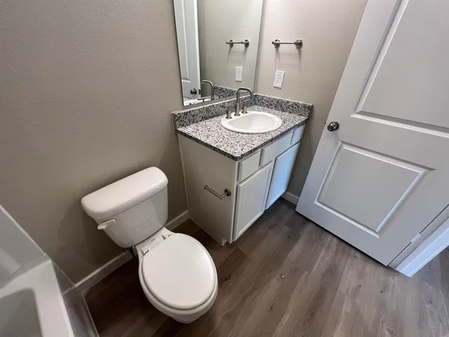 a bathroom with a granite countertop toilet sink and mirror
